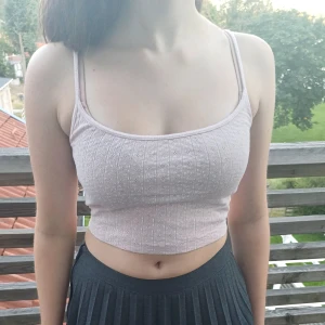 Ljusrosa ribbad croppad linnetopp - Säljer en superfin ljusrosa ribbad croppad linnetopp med vitt blom-mönster från Brandy Melville. Den är ärmlös med smala axelband. Inga defekter eller skador! Perfekt för sommaren eller en festkväll! 🌸