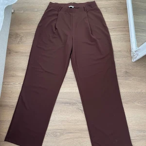 Brun Kostymbyxa Nelly  - Bruna kostymbyxor från Nelly i storlek L. Mjuka i materialet, stretchiga och luftiga. Aldrig använda. 