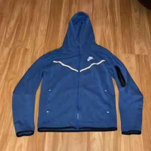 Blå Nike tech fleece - Säljer min blåe Nike tech för att den inte passar. Den är i bra skick men kan vara någon fläck någonstans som knappast syns. Köptes på en JD sports butik i ett köpcentrum i Paris. Storlek 147-158cm