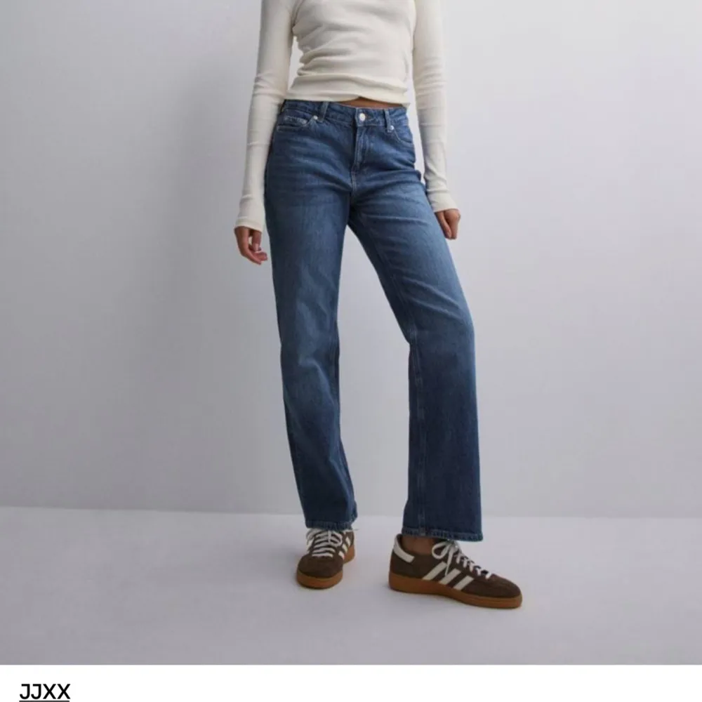 Säljer ett par snygga blå jeans från JJXX. De är högmidjade och har en straight fit som ger en klassisk look. Jeansen är tillverkade i ett slitstarkt denim-material och har en knapp- och dragkedjestängning. Perfekta för både vardag och fest! Köpta på nelly för 599kr. Jeans & Byxor.