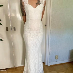 Mermaidklänning i spets från NLY Eve - Helt ny!  Storlek XS  Mermaidklänning i spets från NLY Eve Spetsärmar samt öppen i rygg Knäppning i nacke samt dold dragkedja bak Fodrade kupor för bättre passform Utsvängd nertill Helfodrad 