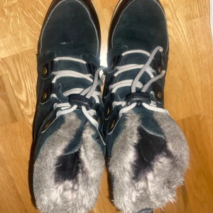 Svarta vinterstövlar från Sorel - Säljer ett par svarta vinterstövlar från Sorel. De är fodrade med mjukt och varmt päls, perfekt för kalla vinterdagar. Stövlarna har snörning framtill och är tillverkade i mocka och skinn. De är i bra skick och redo för en ny ägare! Nypris 1000kr