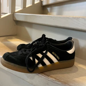 Adidas München sneakers  - Svarta sneakers från Adidas. Köpta secondhand. Använt skick när jag köpte dem. Använda av mig 1-2 gånger. Jättecoola och perfekta till ett par baggy jeans eller svarta kostymbyxor. Bra skick fast tecken på användning finns.