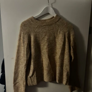 Beige stickad tröja från Pieces - Säljer en supermysig beige stickad tröja från Pieces. Den har en ribbad design och långa ärmar, perfekt för kyliga dagar. Tröjan är i bra skick och passar perfekt till både vardag och mysiga hemmakvällar.