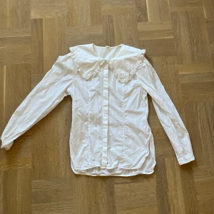 Vit blus med spetskrage - Säljer en superfin vit blus med en stor spetskrage. Den har långa ärmar och knappar framtill. 