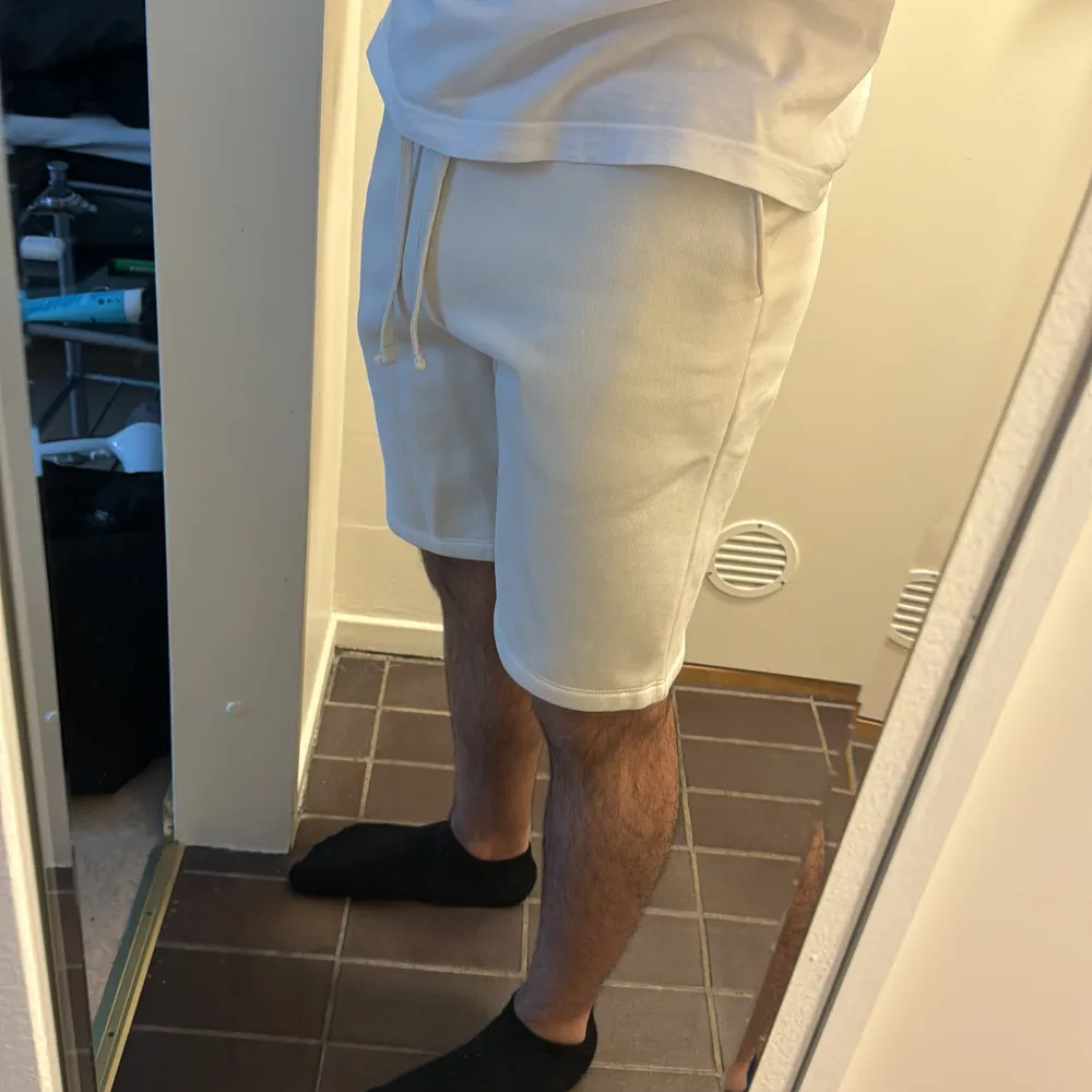 Säljer ett par vita shorts med tryck på sidan. De har en bekväm passform med resår och dragsko i midjan. Perfekta för en avslappnad stil!. Shorts.