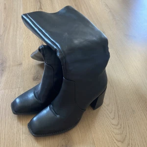 Svarta höga stövletter  - Svarta höga stövletter i storlek 40 med en skafthöjd som når strax under knät.