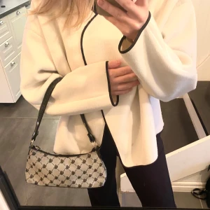 Mönstrad axelväska med svart läderdetalj - Säljer en snygg axelväska med ett coolt mönster i svart och grå. Väskan har en dragkedja upptill + svart läderdetalj på framsidan. Perfekt för både vardag och fest! 🩶🙌🏼 Defekt- välanvänd + två hål på framsidan - de två sista bilderna! därav priset🙌🏼 