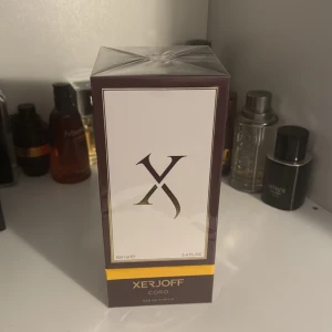 Xerjoff Coro Eau de Parfum - Säljer en lyxig parfym från Xerjoff, modellen Coro. Flaskan är 100 ml och kommer i en elegant mörklila förpackning med gulddetaljer. Perfekt för den som vill ha en exklusiv doftupplevelse. Helt ny och oöppnad!