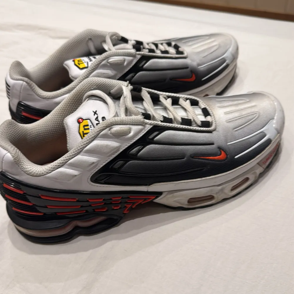 Snygga Nike Air Max sneakers i silver med svarta och röda detaljer. Skorna har en futuristisk design med synlig dämpning i sulan och klassisk snörning. Perfekta för en sportig look.. Kengät.
