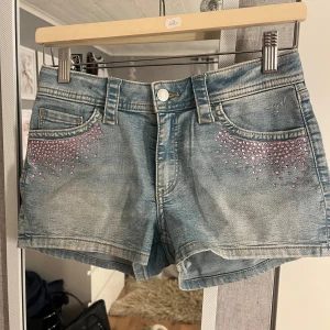 Blå lågmidjade jeansshorts med rosa paljetter från H&M - Ljusblåa jeansshorts med rosa paljetter, shortsen är från H&M barnavdelning i storlek 170. Skulle säga är som storlek xs/s.