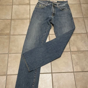 Jacob cohen jeans - Snygga blå jeansbyxor från Jacob Cohen  med klassisk femficksdesign och dragkedja. Perfekta för en avslappnad stil. De har en straight passform och är tillverkade i slitstarkt denim. Storleken är 31