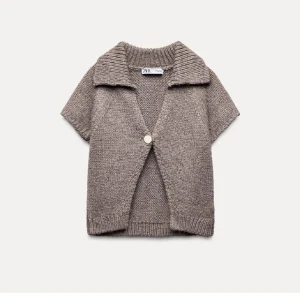 Beige stickad kofta från Zara - Säljer en mysig beige stickad kofta från Zara med korta ärmar och en stor knapp framtill. Perfekt för lager-på-lager under kyliga dagar. Den har en bred krage som ger en extra touch av stil. Använd en gång❤️