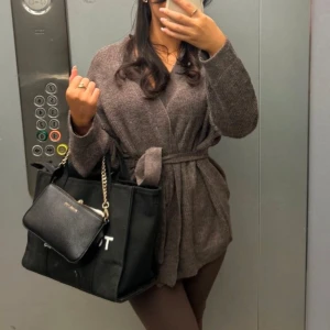 Brun kofta med bälte - Mysig brun kofta med bälte i midjan. Perfekt för kyliga dagar och ger en avslappnad look. Koftan har långa ärmar och en mjuk textur. Även slutsåld 