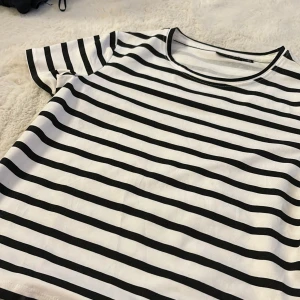 Randig t-shirt från XOXO & friends - Snygg och klassisk svartvit randig t-shirt från XOXO & friends. Perfekt för en avslappnad stil med korta ärmar och rund hals. Tillverkad i mjukt material för extra komfort.🤍