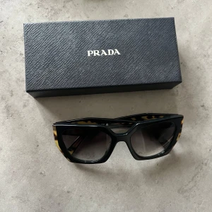 Prada solglasögon  - Solglasögon från prada. Använda ett fåtal gånger. Har ett par små repor (ej på glaset) som endast syns i visst ljus. Alla tillbehör finns kvar.