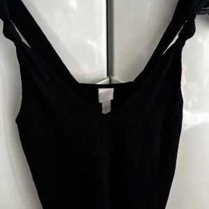 Svart linne från 157 - Snygg svart klänning från 157 med djup v-ringning. Perfekt för en stilren look. Klänningen har en enkel design som gör den lätt att matcha med olika accessoarer.