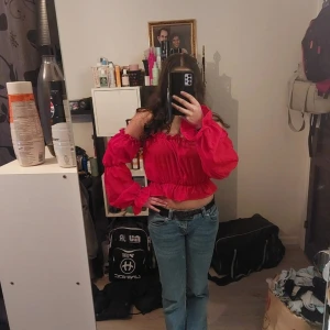 Röd offshoulder blus - Snygg röd offshoulder blus med volangdetaljer och långa ärmar. Perfekt för en trendig look.