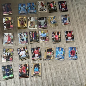 Samling av fotbollskort - Stor samling av fotbollskort som sammanlagtt har ett värde upp till 1500+ så bra för resellers och kommer även en snygg box till med olika teman som 'Titan', 'Golden Baller', 'Fans' Favourite' och 'Limited Edition'. Kort med spelare i olika positioner och från olika klubbar. Perfekt för samlare eller fotbollsfans som vill utöka sin kollektion. 