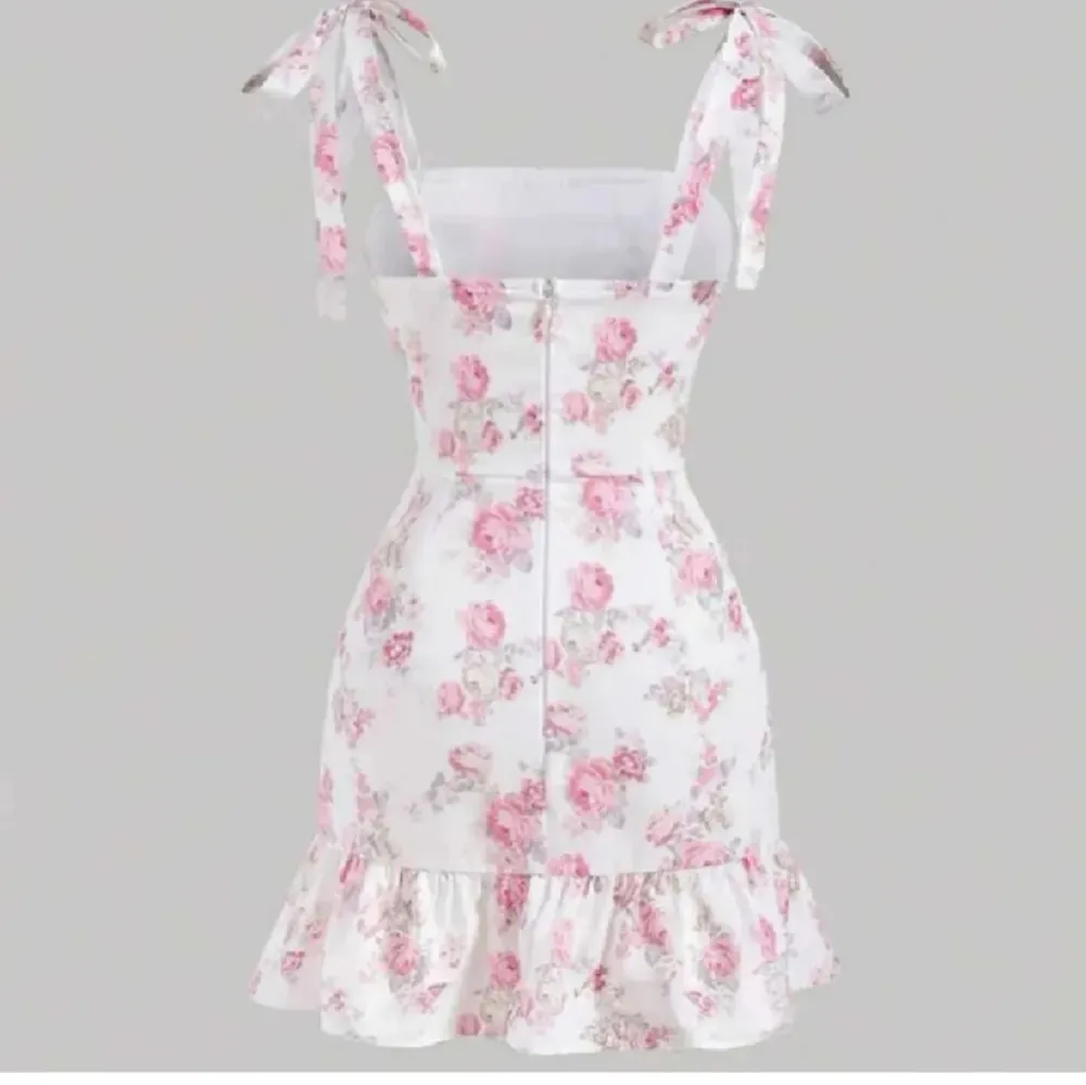 Säljer en superfin blommig klänning i vitt och rosa som aldrig kommit till användning. Den har en söt volangdetalj längst ner och knytband på axlarna. Perfekt för sommarens alla fester och midsommar! Klänningen är kort och har en dragkedja i ryggen.. Mekot.