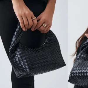 Svart flätad handväska - Snygg svart handväska med flätat mönster. Perfekt för att ge en stilren touch till din outfit. Väskan har en enkel design utan extra detaljer, vilket gör den lätt att matcha med olika stilar.