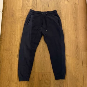 Mörkblå mjukisbyxor med snörning - Säljer ett par mörkblå mjukisbyxor i herrstorlek  M. Byxorna har en bekväm passform med snörning i midjan och ribbade muddar vid bensluten. Perfekta för en avslappnad stil.  Lager 157 nyskick oanvända