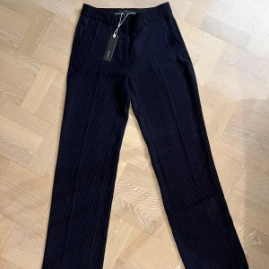 Festliga kritstrecksrandiga byxor med glitter - Snygga svarta byxor från Only med diskreta glittriga ränder. Byxorna har en rak passform och är högmidjade, och faller fint. Aldrig använda, då de är för långa för mig. Prislappen är kvar.