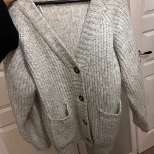 Grå stickad kofta med knappar - Mysig grå stickad kofta med knappar framtill och två praktiska fickor. Tyvärr kommer den inte till användning längre. Passar även för dig som har small och medium.