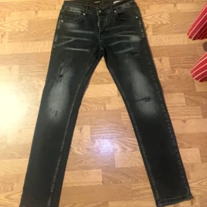 Svarta jeans från Dsquared2 - Snygga svarta jeans från Dsquared2 med slitna detaljer och en straight passform. Tillverkade i Italien med märkets logga på knapp och etikett. Perfekta för en stilren look.