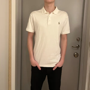 Polo Ralph lauren piké  - Sitter betydligt mindre än L, möjligen pga av slim fit. Säljer en stilren vit pikétröja från Ralph Lauren i slim fit. Tröjan har korta ärmar och en klassisk krage med knappar. Den ikoniska loggan är broderad på bröstet.