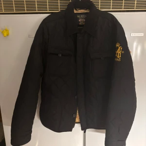 Svart quiltad jacka från Morris - Snygg svart quiltad jacka från Morris med broderad logga på bröstet. Jackan har en klassisk krage och knäppning framtill. Perfekt för höst och vår. Det står XL men funkar verkligen som L. Pris kan diskuteras!:)