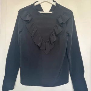 Blus - Svart blus med volang detaljer.  Storlek S Märke: HM
