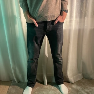 Svarta nudie jeans - Nudie jeans i färgen Dark Cove (svart) och modellen Grim Tim. Mycket bra skick, storlek W31 L32.
