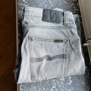 Gråa Nudie jeans - Säljer dessa feta Nudie jeans i modellen lean dean! Storleken på jeansen är 31w/34L. Jeansen är i helt nytt skick och är knappt använda, skriv vid frågor!
