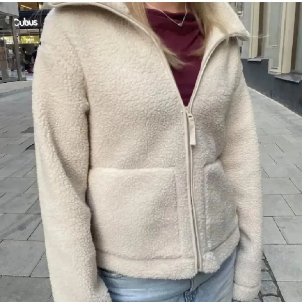 Mysig beige teddyjacka i fleece med dragkedja framtill. Perfekt för höst och vinter, håller dig varm och stilren. Jackan har långa ärmar och två praktiska fickor. Passar både till vardags och lite finare tillfällen.. Jackor.