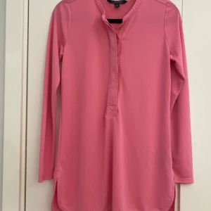 Rosa långärmad topp i strl XS från Ralph Lauren - Rosa långärmad topp i strl XS från Ralph Lauren.  Finns några minimala trådar som lossnat i övrigt i fint begagnat skick.  Mått Över bröstet: ca 48 cm Längd från axeln och ner: ca 71 cm  94% polyester och 4% elastan  Kommer från ett djur och rökfritt hem. 