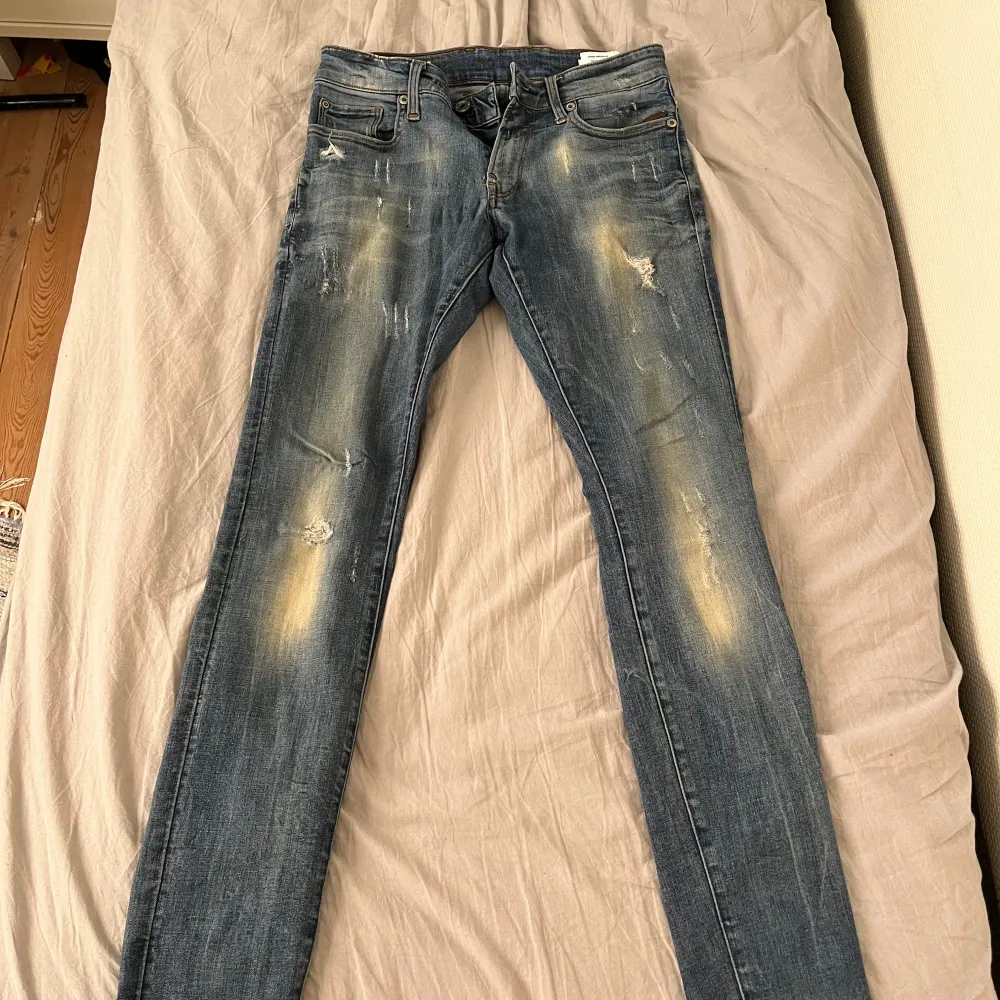 Säljer ett par snygga blå jeans från G-Star RAW i bra skick. De har en cool slitningseffekt och en klassisk femficksdesign. Perfekta för både vardag och fest! Passar dig som gillar en tight passform.. Jeans & Byxor.