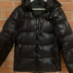 Glansig dunjacka från Polo Ralph Lauren - Säljer min snygga svarta dunjacka från Polo Ralph Lauren. Jackan är glansig och i mycket bra skick. Köpt förra året och sparsamt använd, storlek S! Nypris 6095 kr. Hör av dig vid fler frågor 😊