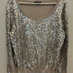 Glittrig beige tröja med silverpaljetter - Säljer en superglittrig tröja täckt med silverpaljetter. Perfekt för fest eller nyår! Tröjan har långa ärmar och en rund halsringning. Den är i bra skick och redo att ge din outfit det där lilla extra. ✨