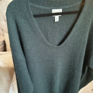 Mörkgrön stickad tröja - Säljer en mysig mörkgrön stickad tröja i storlek M. Den har en v-ringad hals och långa ärmar, perfekt för kyliga dagar. Tröjan är i bra skick och passar både till vardags och lite finare tillfällen. Perfekt för höst och vinter!