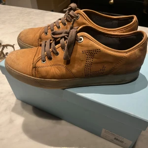 Lanvin skor - Säljer ett par snygga bruna sneakers från Lanvin i skinn. Riktigt unika med l:et på sidan av skon. Skorna är i bra skick med lite slitage på sulan. Perfekta för både vardag och fest! Kan behövas putsas upp lite. Vid några frågor är det bara att höra av sig. Låda och ett par extra snören tillkommer. Priset går att diskutera!