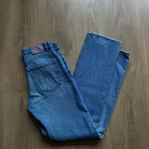 Blå jeansbyxor - Säljer ett par klassiska blå jeans med med mid waist. De har en straight passform vilket ger en snygg och bekväm stil. Perfekta för både vardag och fest! 🕺De är lappade där bak men inget som syns’