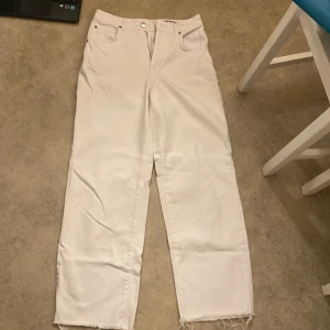 Vita jeans från Never Denim - Säljer ett par vita jeans från Never Denim i 90-talsstil. De har en straight passform och är i mycket bra skick. Perfekta för både vardag och fest! De är högmidjade och har en snygg fransdetalj vid bensluten. Passar perfekt till en avslappnad look eller att klä upp med en snygg topp.