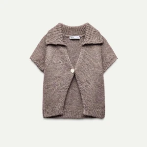 Beige stickad kofta från Zara - Säljer en superfin beige stickad kofta från Zara. Den har korta ärmar och en stor knapp framtill. Perfekt för lager-på-lager under hösten eller våren. Koftan har en mysig och avslappnad stil, perfekt för både vardag och lite finare tillfällen.