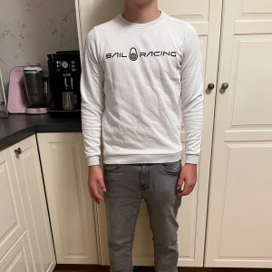 Vit långärmad tröja från Sail Racing - Säljer en stilren vit långärmad tröja från Sail Racing. Den har en snygg logga på bröstet och en mindre på ryggen. Perfekt för en casual look eller en dag på stan. Jag på bilden ör 160. Pris kan diskuteras vid snabb affär 