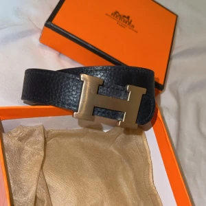 Svart skärp kopi1 - Säljer ett elegant svart skärp  i skinn med en ikonisk H-spänne i guld. Perfekt för att ge en lyxig touch till vilken outfit som helst. Kommer i originalförpackning. Passar både till vardag och fest! Fick den som present men inte riktigt min stil 🤍