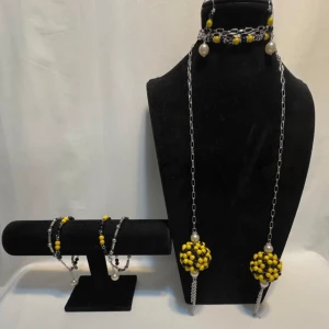 Handgjorda smycken med pärlor i gult och svart - Unika handgjorda smycken med stora gula och svarta pärlor. Setet inkluderar ett halsband, armband och örhängen. Kedjorna är i silverfärg och smyckena har en modern och iögonfallande design. Perfekt för att liva upp en outfit med lite färg och stil! Ett par örhängen och ett par armband plus en halsband handgjorda mycket mycket fint nytt oanvänd 