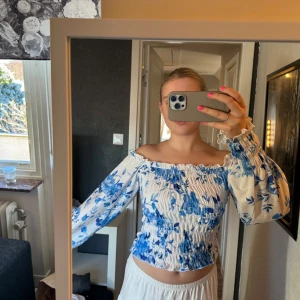 vit offshoulder blus med blå blommor🩵 - Supergullig vit offshoulder blus med blåa blommor, mittendelen samt ändarna på ärmarna i ribbat tyg🩵 Använd bara någon gång så i nytt skick🤍