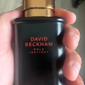 David Beckham Bold Instinct Parfym - Säljer en elegant och maskulin parfymflaska från David Beckham, Bold Instinct. Storlek 30 ml men typ 25 kvar i den. Flaskan är svart med guldlock och har en stilren design. Perfekt för den självsäkra mannen som vill ha en doft som varar hela dagen. Passar både till vardags och fest.