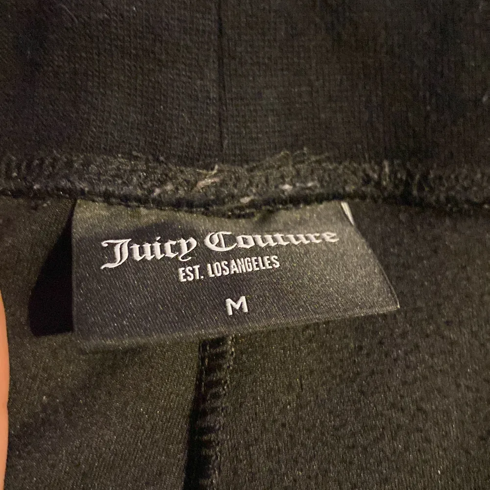 Säljer ett par svarta mjukisbyxor från Juicy Couture i storlek M. Byxorna är i mjukt material och har snygga strassdetaljer med JC-loggan. Perfekta för en avslappnad dag hemma eller en stilren look på stan. De har en bekväm resårmidja med snörning.. Jeans & Byxor.